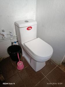 a white toilet in a bathroom with a black bucket at Qusar Eniğ kend in Qusar