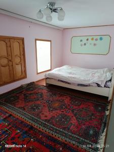 a bedroom with a bed and a rug and a window at Qusar Eniğ kend in Qusar