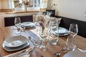 a wooden table with plates and wine glasses on it at Bergschatz in Wildschönau +18 photos