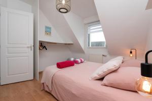 a bedroom with a pink bed with red pillows on it at Maison Ker Galeret in Sarzeau