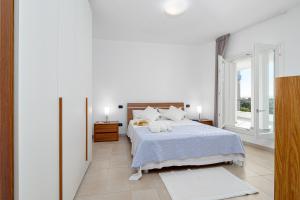 a white bedroom with a bed and two windows at Villa Marconi Apartment 9 in Golfo Aranci
