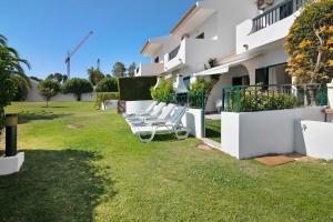 a row of white lounge chairs in the yard of a building at Villa Janeca in Albufeira