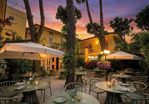 ein Freiluftrestaurant mit Tischen, Stühlen und Bäumen in der Unterkunft JR Resort Logos Forte dei Marmi in Forte dei Marmi + 31 Fotos