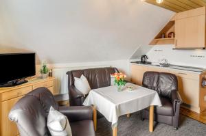 a living room with a table and chairs and a kitchen at Ferienwohnung Karin in Marienhafe