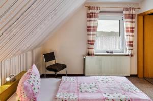 a bedroom with a bed and a window and a chair at Ferienwohnung Karin in Marienhafe