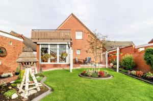 a house with a yard with a garden with flowers at Ferienwohnung Karin in Marienhafe