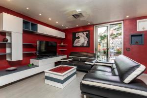 a living room with red walls and a black leather couch at Tao Rama Suite in Taormina