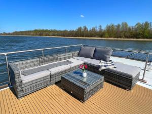 a couch and a table on the deck of a boat at Gemütliches Hausboot Seeliebe Woma in Fürstenberg