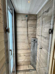a bathroom with a shower with a wooden wall at Gemütliches Hausboot Seeliebe Woma in Fürstenberg
