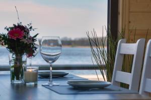 a table with a glass of wine and flowers on it at Gemütliches Hausboot Seeliebe Woma in Fürstenberg +5 photos