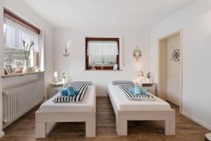two beds in a white room with a window at bleib. Boutique Premium Lake House in Allensbach