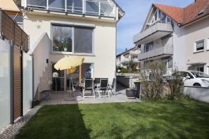 a white house with a patio and an umbrella at bleib. Boutique Premium Lake House in Allensbach