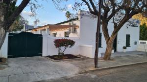 a white house with a green gate and a tree at De Kothuize 2 in Graaff-Reinet +1 photo