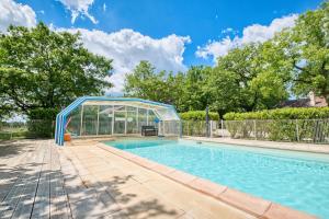 a swimming pool with a glass house around it at Chalet Rapiette in Salignac Eyvigues