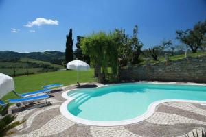 a swimming pool in a yard with two chairs and an umbrella at Re Piano appartamento Le Colline in Modigliana