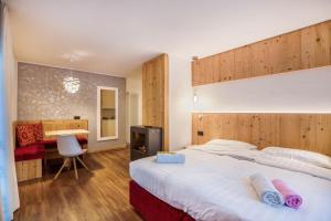 a hotel room with a large bed and a desk at Chalet Osmar Suite 1 in Campitello di Fassa