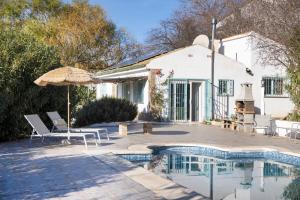 a house with a swimming pool and an umbrella at Finca Carrion in Periana
