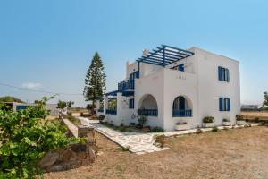 a white house with blue windows and a yard at Galanos Studios Naxos in Naxos Chora