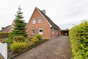 a red brick house with a cobblestone driveway at Haus Gartenidylle in Wesselburen