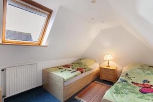 two twin beds in a attic bedroom with a window at Haus Gartenidylle in Wesselburen