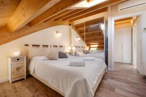 a bedroom with a large white bed with wooden ceilings at Summer and Winter in Perledo