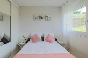 a bedroom with a bed with pink and white pillows at Appartement en front de mer in Plérin +12 photos