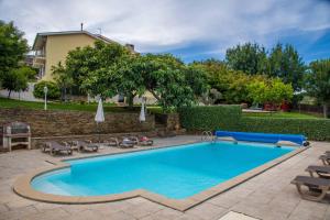 a swimming pool with chairs and umbrellas in a yard at Recanto Transmontano in Macedo de Cavaleiros
