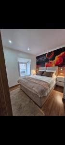 a bedroom with a large bed with a large painting on the wall at Origens - Alojamento Local in Bragança