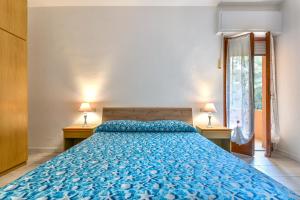 a bedroom with a large blue bed with two lamps at Casa Claudia a Porto Azzurro in Porto Azzurro