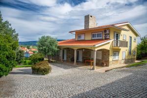 a large yellow house with a brick driveway at Recanto Transmontano in Macedo de Cavaleiros