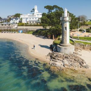 a lighthouse on the beach with a person walking on the sand at Studio Turquoise à 100m de la plage in Bénodet