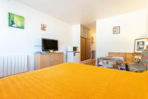 a bedroom with a yellow bed and a television at Studio Turquoise à 100m de la plage in Bénodet