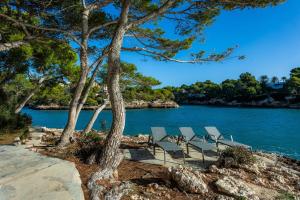 a group of chairs sitting next to a body of water at Ferrera Suite in Cala Ferrera