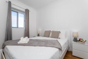 a white bedroom with a large bed with a window at Oásis Fonte Grande in Santo António