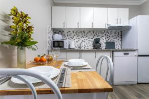 a kitchen with white cabinets and a wooden table at Oásis Fonte Grande in Santo António +35 photos
