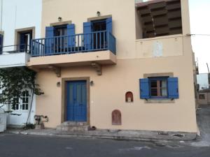 a building with blue windows and blue shutters at Emma's maisonette house by Kapsali beach in Kapsali