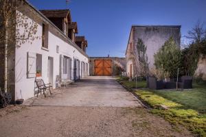 an alley with a wooden door on a white building at Chambres D'hôtes Le Petit Puits in Cheverny