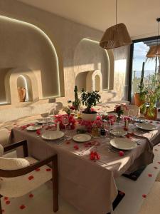 a dining room with a long table with red flowers on it at Coral Boutique Hotel in Vlorë +66 photos