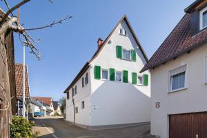 a white house with green windows on a street at Ferienwohnung Sila 3 in Weinstadt