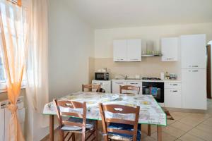 a kitchen with a table with chairs and white cabinets at Il Frutteto 48 in Ortovero