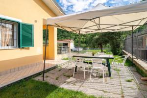 a patio with a table and chairs under an umbrella at Il Frutteto 48 in Ortovero