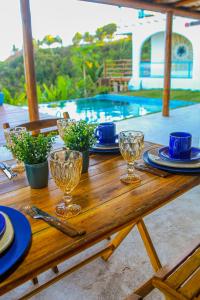 a wooden table with plates and wine glasses on it at Casa Edom - Maceió in Maceió