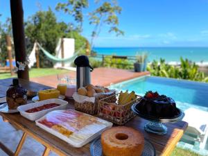 a wooden table with food on it with a pool at Casa Edom - Maceió in Maceió