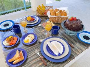 a table with blue plates of food and a cake at Casa Edom - Maceió in Maceió