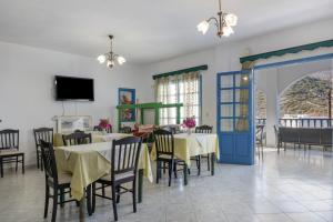 a dining room with tables and chairs and a tv at Hotel Glaros Karpathos in Karpathos