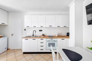 a kitchen with white cabinets and a sink and a table at VICE by Apiro Syros in Ermoupoli +11 photos