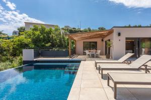 a swimming pool with chairs and a house at Villa Belenos Piscine vue mer in Roquebrune-sur-Argens