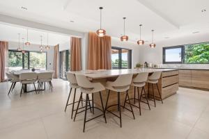 a kitchen with a large wooden table and bar stools at Villa Belenos Piscine vue mer in Roquebrune-sur-Argens