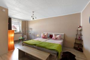 a bedroom with a bed with green sheets and pink pillows at Wohnung Im Hinterhof in Querfurt