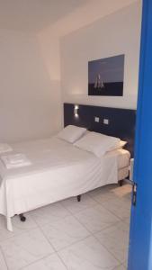 a bedroom with a white bed with a painting on the wall at Hotel Lagoinha in Ubatuba